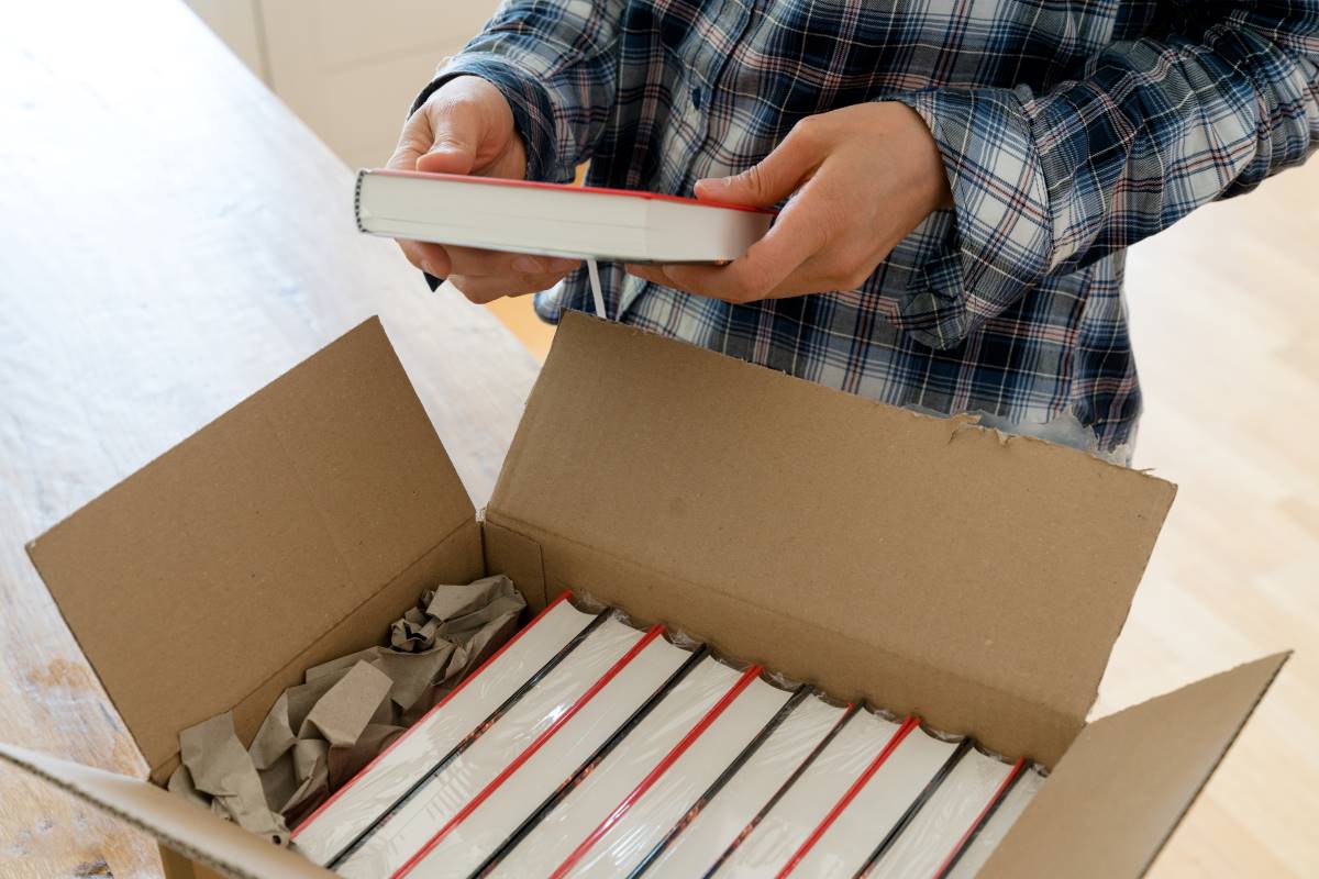 A man examining a brand-new book from a box full of books