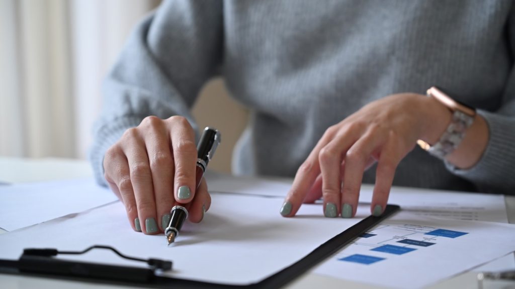 A woman with painted nails going over documents with a pen