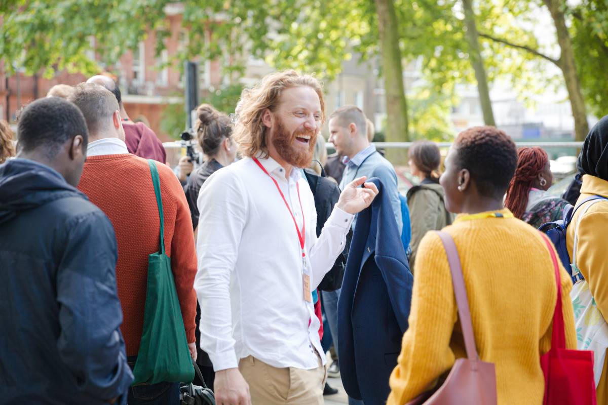 A smiling man talking to a woman in a crowd of people