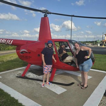 A helicopter on a heli pad with James Courtney standing next to it.