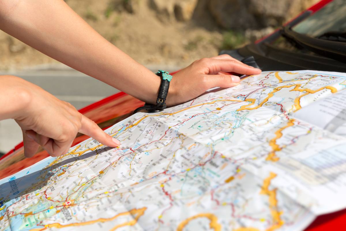 A woman reading a map on the hood of a car