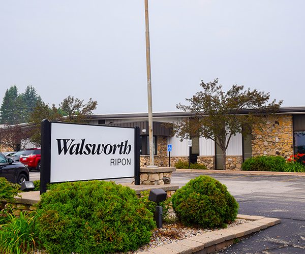 A large sign that says Walsworth in a parking lot in front of a building