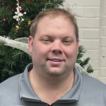 Ryan Sebacher standing in front of a Christmas tree smiling