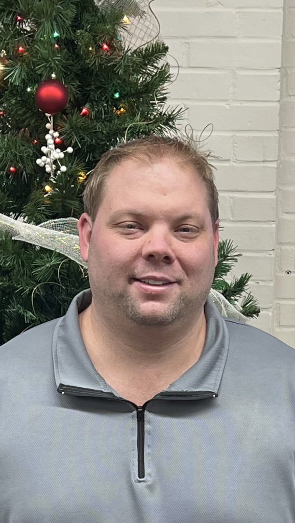 Ryan Sebacher standing in front of a Christmas tree smiling